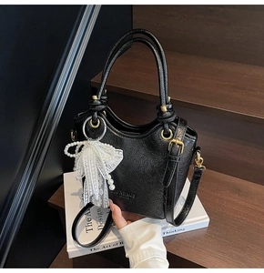 Gros plan détaillé d'un sac seau noir avec texture froissée brillante et breloque nœud perlé