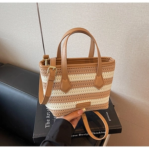 Detail of knitted stripe bucket bag with brown leather handles and premium stitching