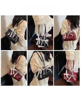 Detail view of large shoulder bag with lace bow, ribbon, and heart metal pendant details
