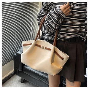 Detail view of the cream leather tote bag with brown straps and golden twist lock closure