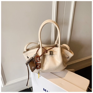 Detail of beige PU leather dumpling bag with heart tassel charm and metal buckle