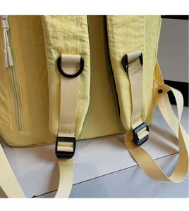 Detail view of adjustable padded shoulder straps and D-rings on yellow nylon backpack