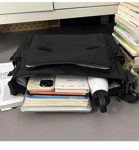 Internal view of black messenger bag showing capacity for laptop, books and water bottle