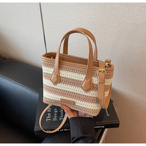 Detail of the woven texture and brown leather strap on this striped straw beach handbag