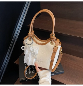 Détail du sac seau crème avec bordure marron et pendentif nœud en perles dentelle