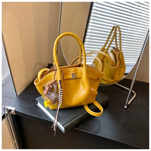 Detail of yellow crossbody bag with pleated design and heart-shaped leather tassel charm