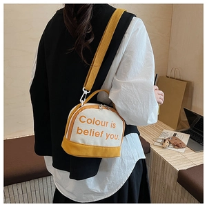 Detail of canvas bowling bag with yellow strap worn as a stylish crossbody bag