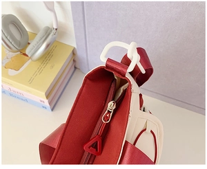 Detailed macro view of the red and white crossbody bag with nylon strap and zipper detail