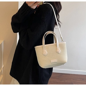 Close-up of beige woven straw handbag with leather handles and textured grid pattern