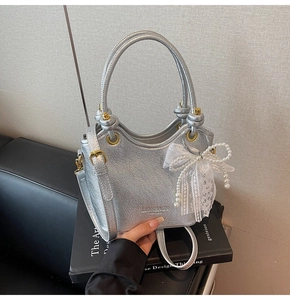 Détails du sac à main en cuir argenté avec nœud en dentelle et perles et logo