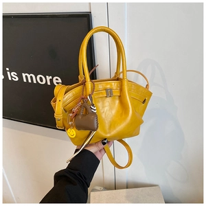 Detail of yellow crossbody bag with decorative charms and polished nappa texture