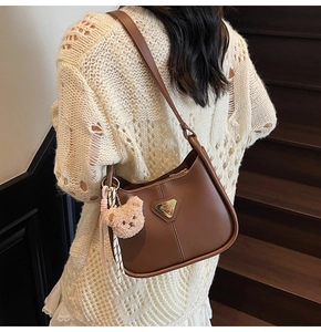 Détail du sac à bandoulière en similicuir marron avec breloque ours et foulard décoratif