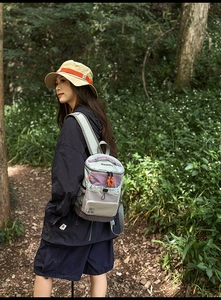 Detailed outdoor view of a colorful hiking backpack with a sun hat and jacket in the woods