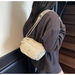Detail of beige wrinkled nylon crossbody bag featuring multi-zipper pockets and wide strap