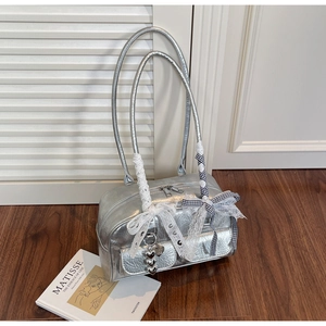 Close-up of silver Boston bag with lace ribbon, checkered bow, and heart pendant