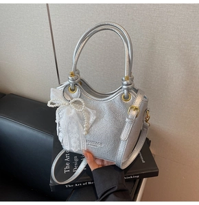 Détail du sac en cuir argenté métallisé avec texture craquelée et nœud en dentelle