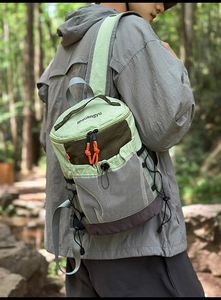 Detail of light green hiking backpack featuring orange zipper pulls and side mesh pocket