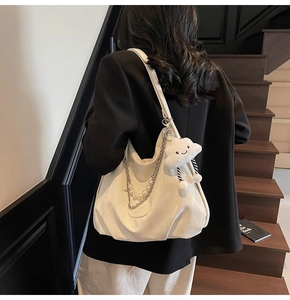 Détail du sac cabas blanc avec chaîne argentée, bandoulière perle et breloque nuage