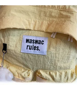Detailed macro view of yellow canvas backpack with textured fabric and soft white pom-pom