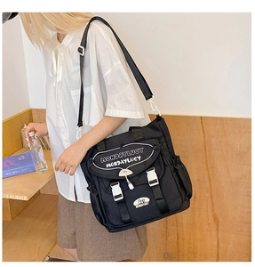 Detail of black canvas crossbody bag with white buckles and MONDAYLUCY branding logo