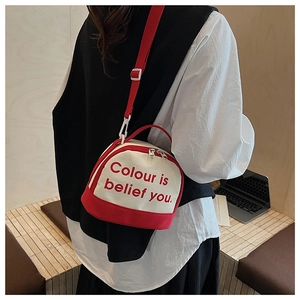 Detail of red and white bowling bag with slogan print worn by model in a cozy setting
