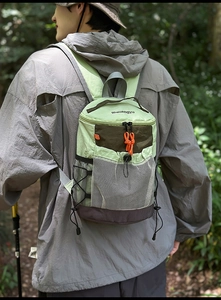 Outdoor light green hiking backpack with orange zipper accents on a model in nature