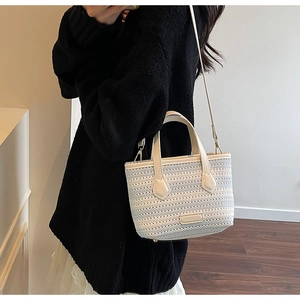Detailed close-up of ivory knitted bucket bag showing fine texture and leather emblem