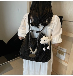 Détail du sac plissé noir avec chaîne argentée, perle et pendentif nuage pelucheux