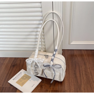 Detail of cream PU leather handbag featuring lace bows and metal heart pendant
