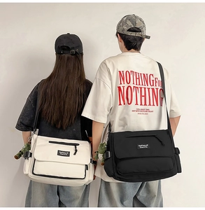 Detail of black and white canvas messenger bags with cute dinosaur charms on models