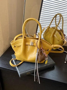 Bright yellow textured leather handbag with heart charm on a black book for fashion decor