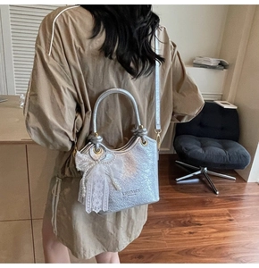 Détail du sac seau métallisé argenté avec nœud en dentelle et perles blanches