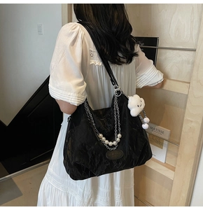 Détail du sac plissé noir avec chaînes argentées, perles et charm nuage peluche