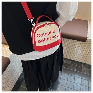 On-body view of a small red and white canvas bowling bag with crossbody strap and handles