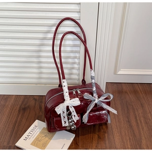 Detail of dark red glossy patent leather shoulder bag with chic lace bow ornaments