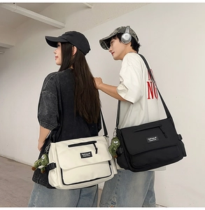 Neutral messenger bag featuring flap design with adjustable strap and plush dinosaur charm