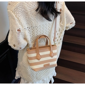 Detail of striped knitted bucket bag with leather handles and strap on a model