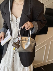Silver metallic dumpling handbag with cross-body strap and mini charm for women