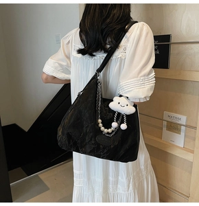 Détail du grand sac hobo noir avec chaîne argentée, bandoulière perle et gris-gris nuage