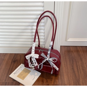 Deep red patent leather shoulder bag detail with lace trim and heart charm