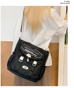 Detail of black nylon messenger bag with white buckles and embroidery for daily commute