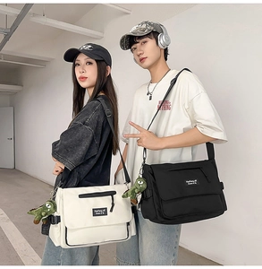 Detail of black and white large canvas messenger bags with cute dinosaur pendants