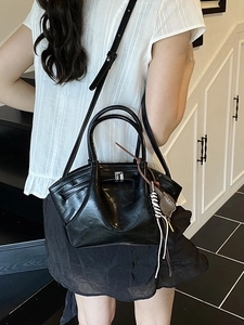 Minimalist black glossy leather crossbody tote bag with silver buckle and braided charm