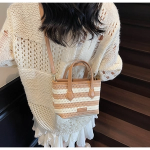 Detail view of striped knitted bucket bag with leather handles and beige woven texture