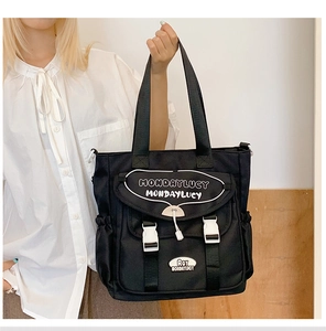 Detail of black canvas tote bag showing the white contrast buckle and MondayLucy print