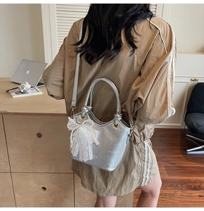 Sac seau argenté avec texture craquelée et nœud en dentelle porté en bandoulière