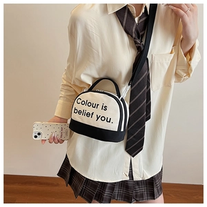 Chic cream and black contrast canvas bowling bag shown as a crossbody on model