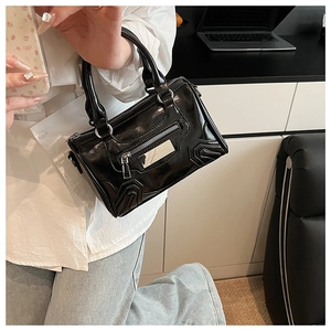 Detalle de cerca de bolso de cuero brillante negro con logo plateado y bolsillo con cremallera