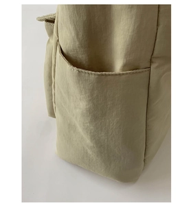 Detail of khaki ripstop nylon bag side pocket showing reinforced double-line stitching