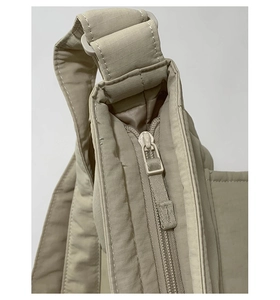 Close-up of the adjustable strap and zipper detail on the khaki ripstop nylon tote bag